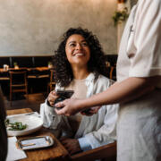 Woman using smartphone while paying restaurant bill with contactless payment during dinner party with friends analítica de pagos